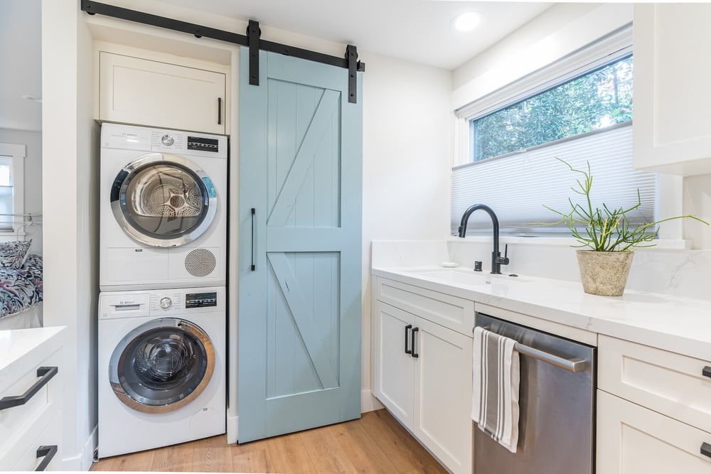 Crow Stacked Washer and Dryer with Blue Barn Door inside an ADU