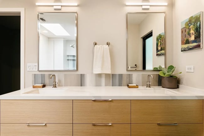 Modern bathroom with double vanity, wood cabinetry, and large mirrors in Sacramento by MAK Design + Build
