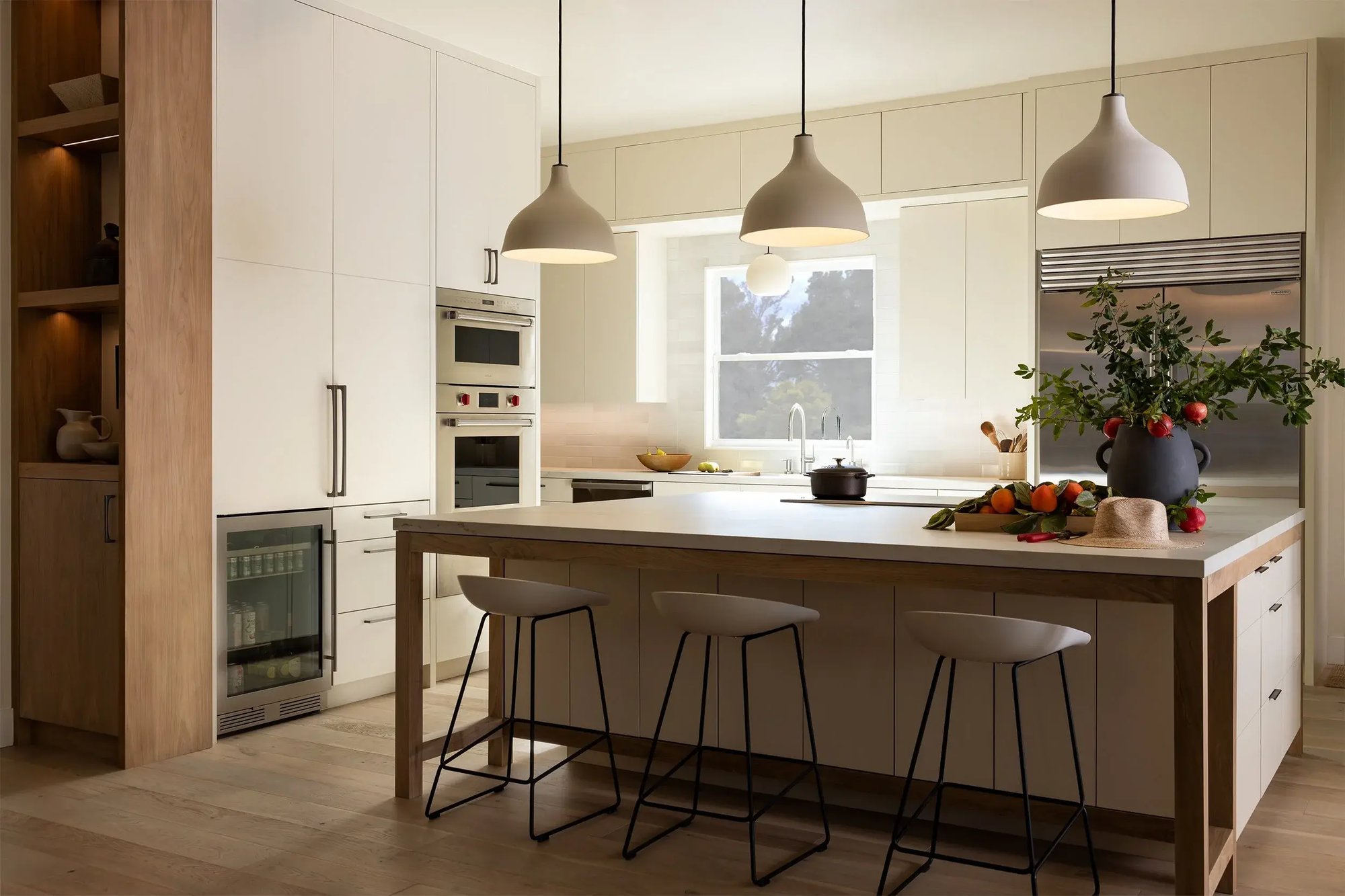 Modern kitchen with large island, pendant lights, and white cabinetry in Sacramento by MAK Design + Build