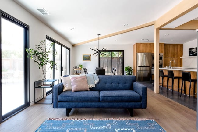 Open living room with blue sofa and view into kitchen in Sacramento by MAK Design + Build