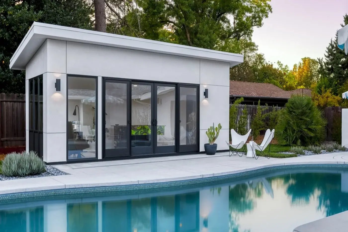 Modern backyard ADU with large glass doors and poolside view in Sacramento by MAK Design + Build