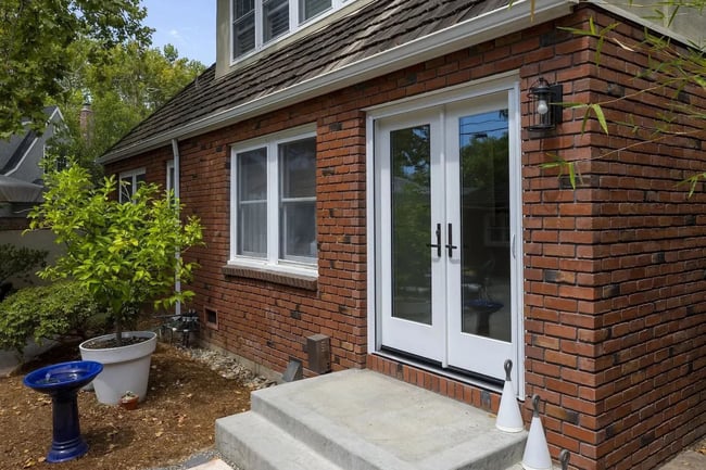 Brick home exterior with white French doors and small patio in Sacramento by MAK Design + Build